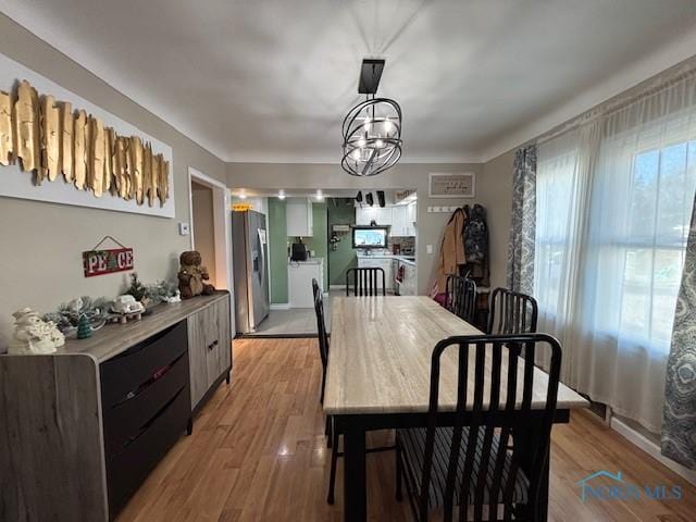 dining space featuring light wood-type flooring and a notable chandelier