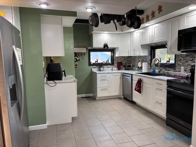 kitchen featuring black appliances, white cabinetry, sink, backsplash, and light tile patterned floors