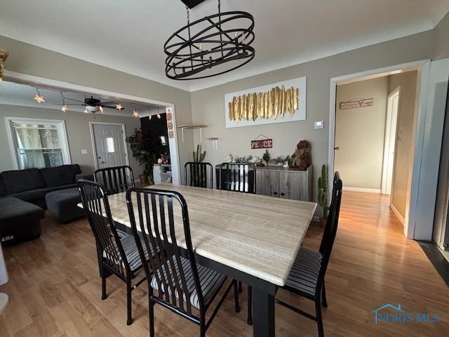 dining room with ceiling fan with notable chandelier and hardwood / wood-style flooring