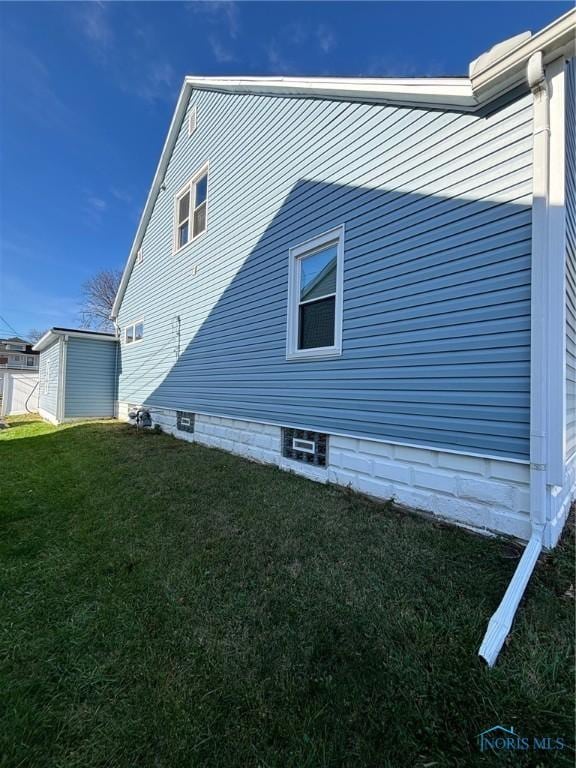 view of side of home with a storage unit and a yard