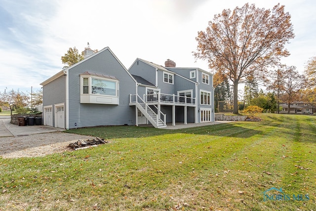 rear view of property with a yard, a wooden deck, and a garage