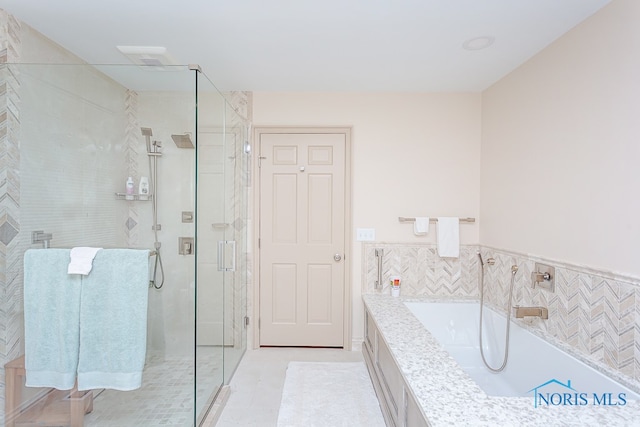 bathroom featuring plus walk in shower, tile patterned floors, and tile walls