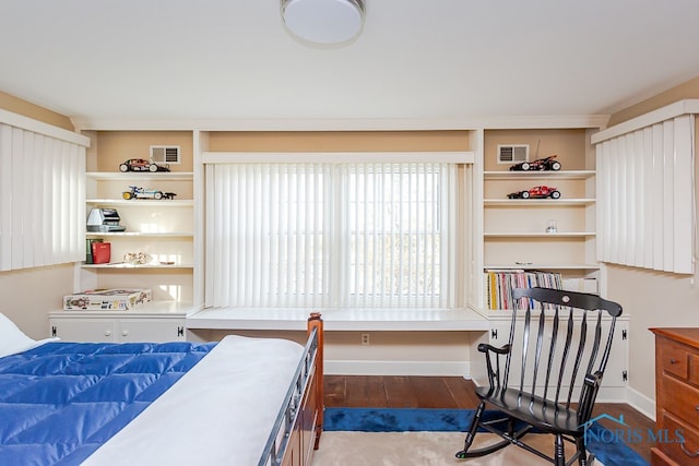 bedroom with built in desk and hardwood / wood-style flooring