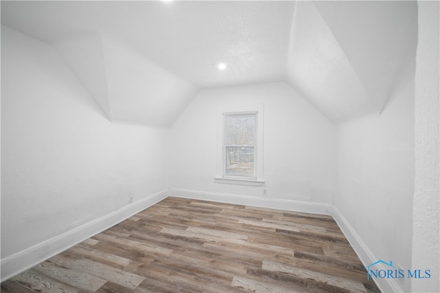 additional living space with vaulted ceiling and light hardwood / wood-style flooring