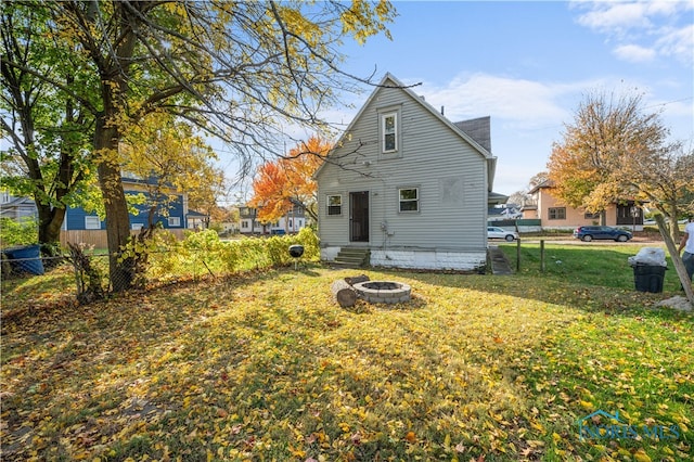 back of property with an outdoor fire pit and a lawn