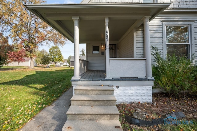 entrance to property with a porch and a lawn