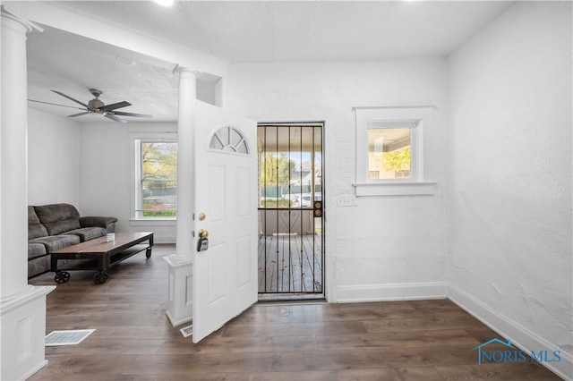 foyer featuring a textured ceiling, ceiling fan, dark wood-type flooring, and decorative columns