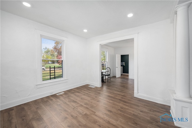 spare room with dark wood-type flooring and decorative columns