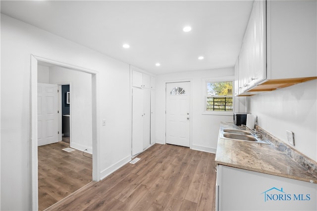 kitchen featuring sink, white cabinetry, and light wood-type flooring