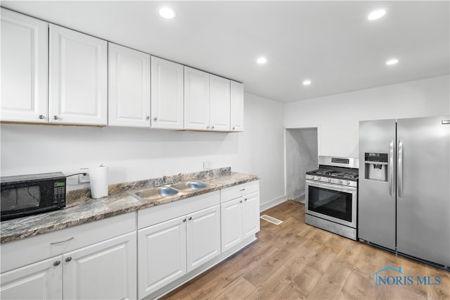 kitchen featuring light stone counters, white cabinetry, sink, light hardwood / wood-style floors, and stainless steel appliances