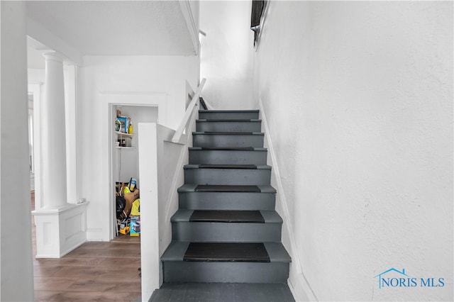 staircase featuring ornate columns and hardwood / wood-style flooring