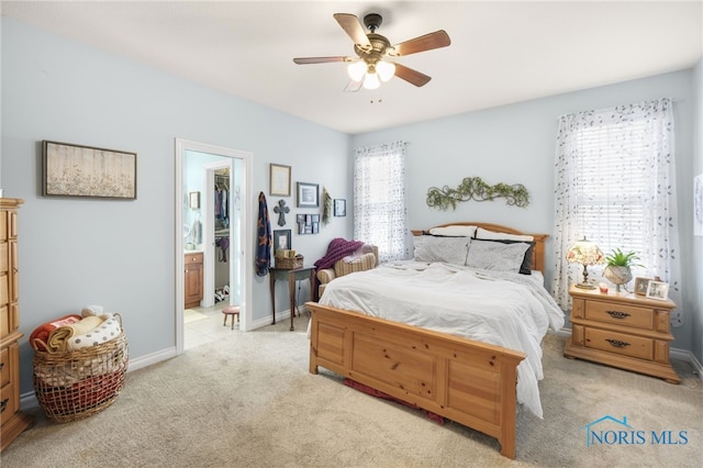 bedroom featuring a walk in closet, light colored carpet, connected bathroom, and ceiling fan