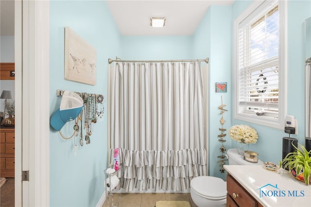 bathroom with vanity, toilet, a healthy amount of sunlight, and tile patterned flooring