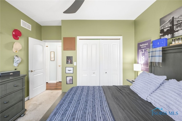 bedroom with a closet, light colored carpet, and ceiling fan