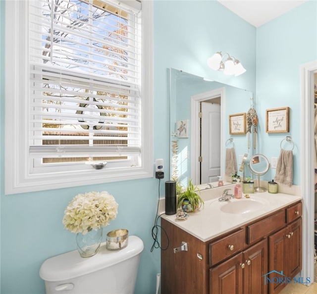 bathroom featuring toilet, vanity, and plenty of natural light