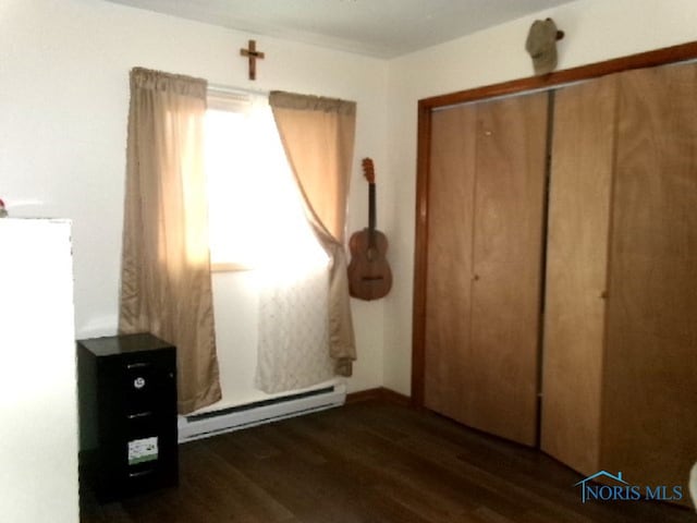 unfurnished bedroom featuring baseboard heating, dark hardwood / wood-style floors, and a closet