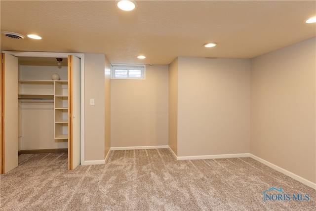 basement featuring carpet flooring and a textured ceiling