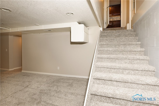 stairway with carpet and a textured ceiling