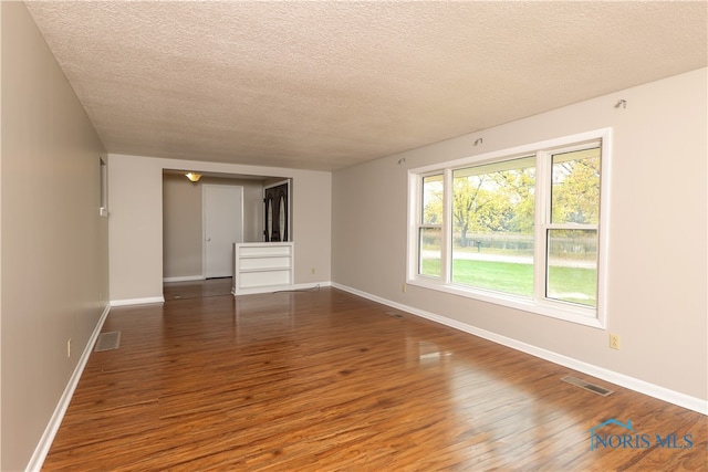 unfurnished room with a textured ceiling and dark hardwood / wood-style floors