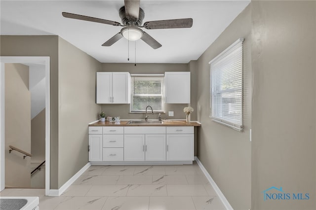 kitchen with white cabinetry, sink, and ceiling fan