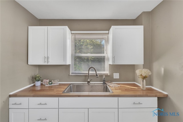 kitchen featuring white cabinets, wooden counters, and sink