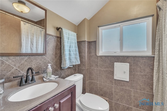 bathroom featuring lofted ceiling, toilet, tile walls, vanity, and walk in shower