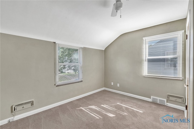 carpeted spare room featuring ceiling fan, a healthy amount of sunlight, and vaulted ceiling