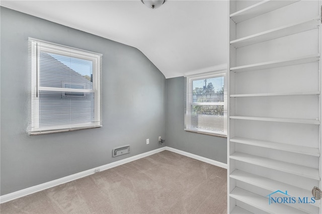 carpeted empty room featuring lofted ceiling