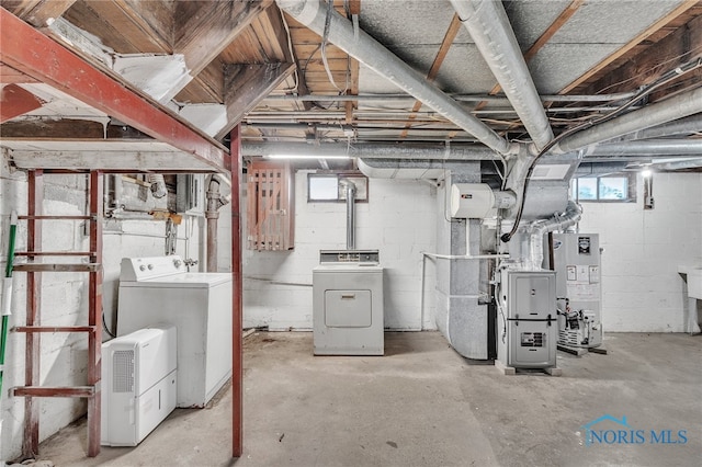 basement featuring water heater, washer and dryer, and heating unit