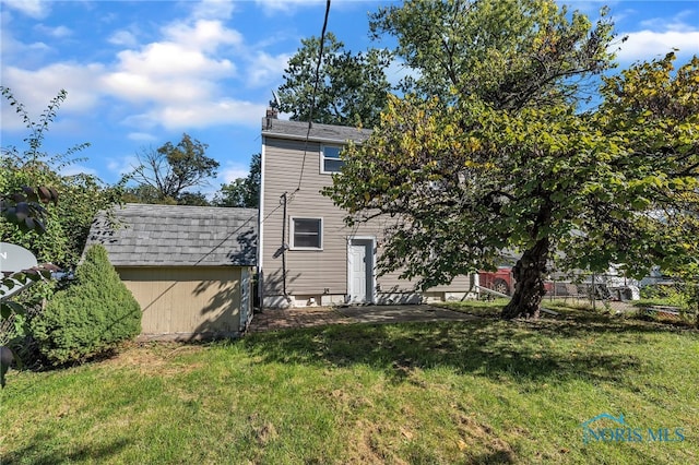 back of property featuring a storage unit and a lawn