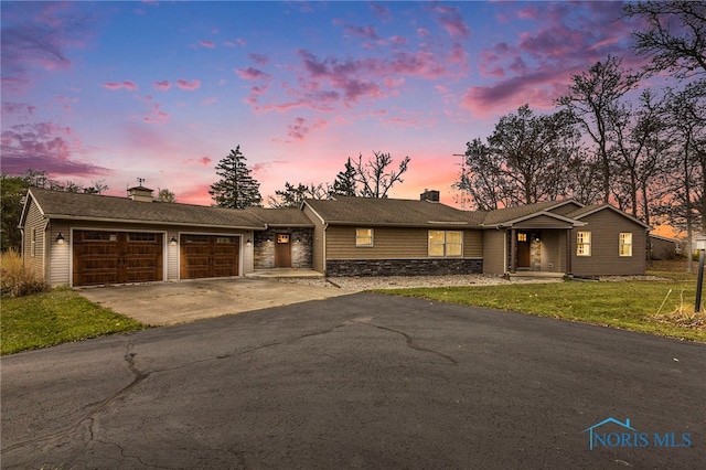 ranch-style house featuring a garage and a yard