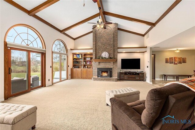 carpeted living room featuring ceiling fan, plenty of natural light, high vaulted ceiling, and a brick fireplace