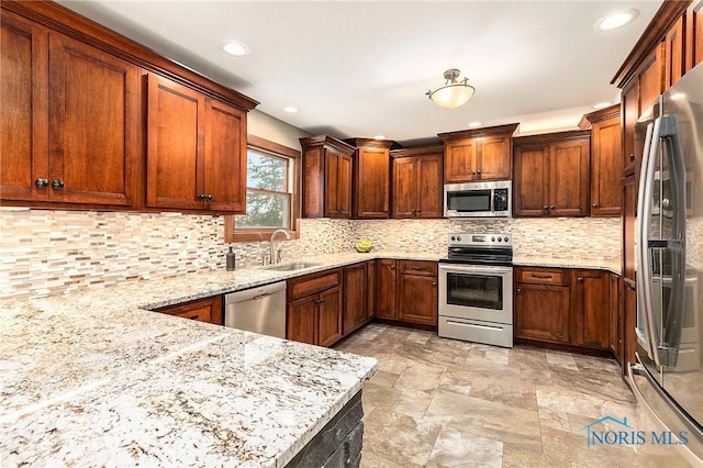 kitchen with sink, backsplash, stainless steel appliances, and light stone countertops