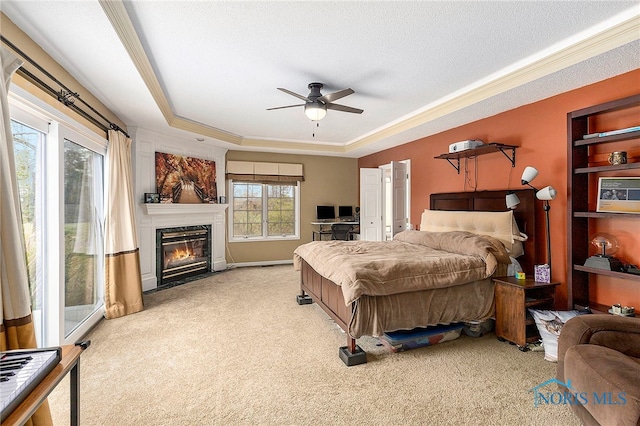 bedroom featuring a raised ceiling, ceiling fan, a fireplace, and light carpet