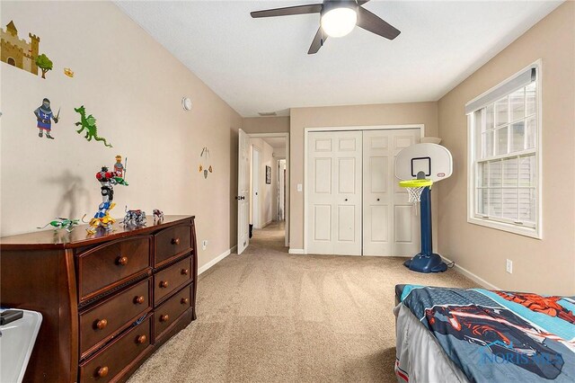 bedroom with ceiling fan, a closet, and light colored carpet