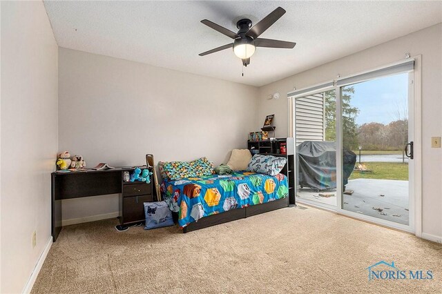 bedroom featuring access to exterior, a textured ceiling, light colored carpet, and ceiling fan