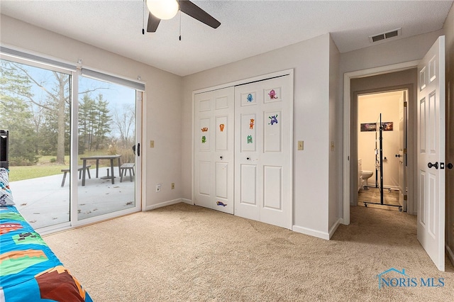 unfurnished bedroom with access to outside, a textured ceiling, light colored carpet, and ceiling fan