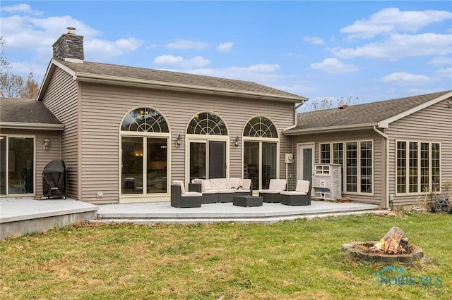 rear view of property featuring a yard, a patio, and an outdoor living space with a fire pit