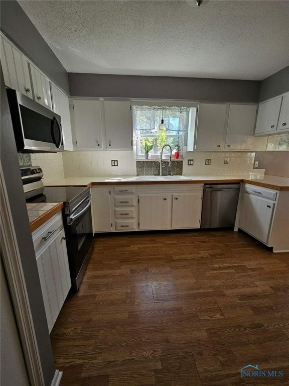 kitchen with white cabinetry, sink, dark wood-type flooring, tasteful backsplash, and appliances with stainless steel finishes