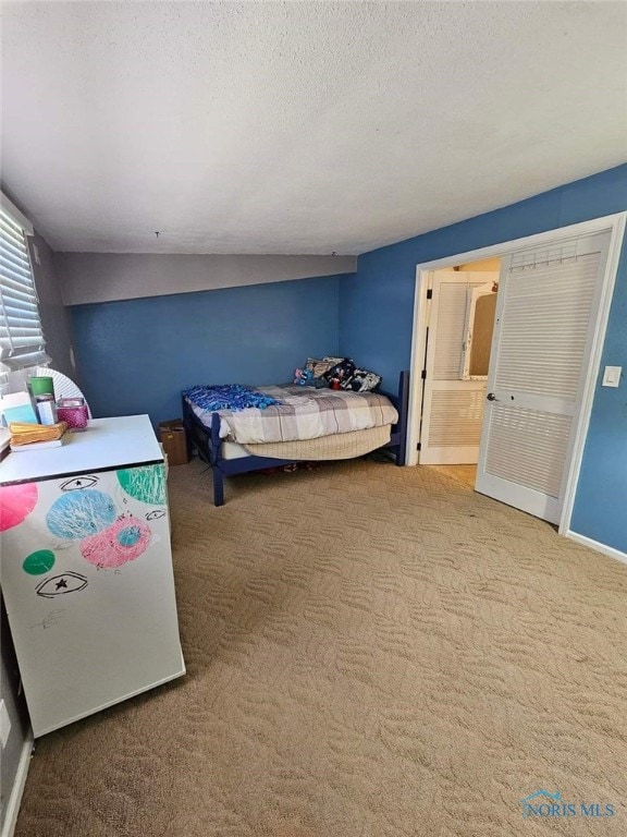 bedroom with a textured ceiling, ensuite bath, carpet floors, and lofted ceiling