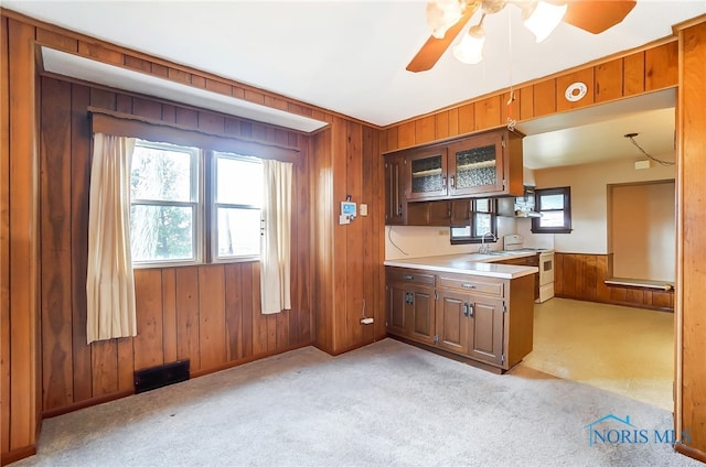 kitchen with white range with electric cooktop, light carpet, wood walls, sink, and ceiling fan