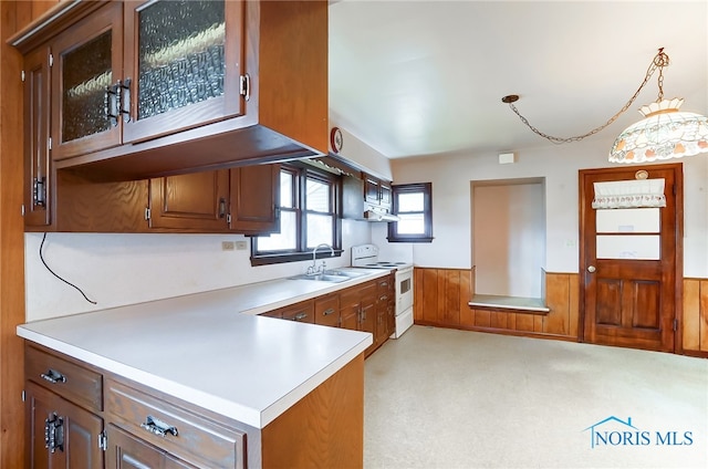 kitchen featuring electric stove, kitchen peninsula, wood walls, sink, and pendant lighting