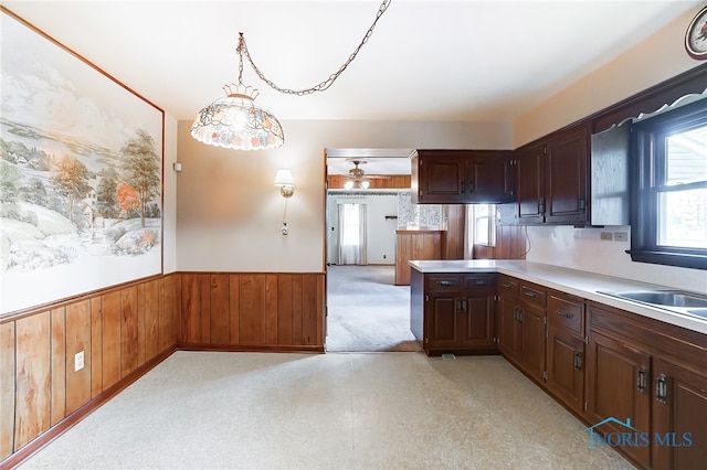 kitchen with wood walls, light colored carpet, and pendant lighting