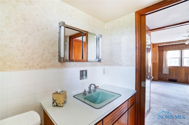 bathroom featuring toilet, vanity, ceiling fan, and tile walls