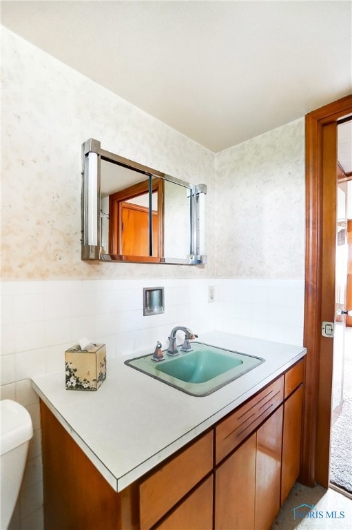 bathroom featuring toilet, vanity, and tile walls