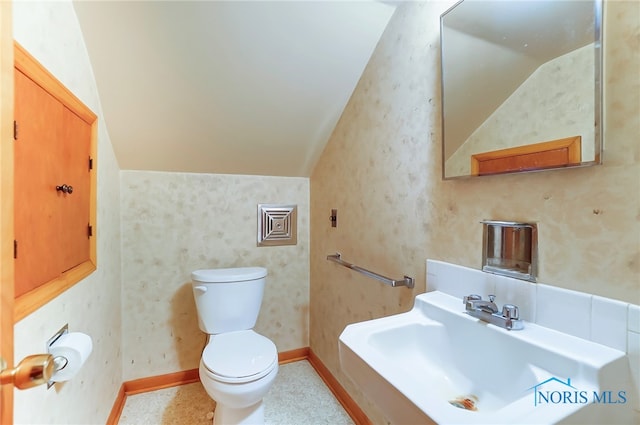 bathroom featuring toilet, lofted ceiling, and sink