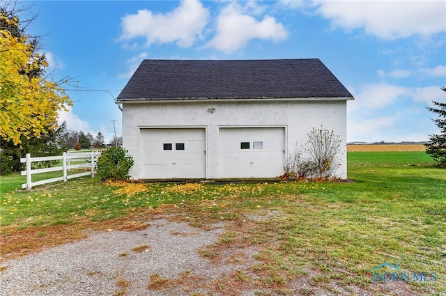 garage featuring a lawn and a rural view