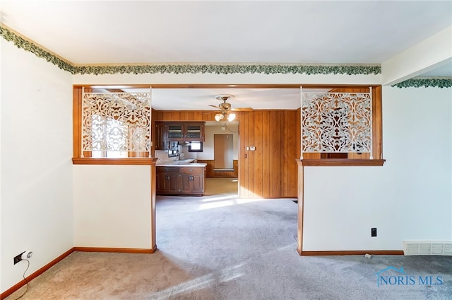 spare room featuring wooden walls, light colored carpet, and ceiling fan