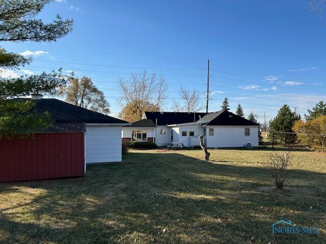 back of house with a storage unit and a yard