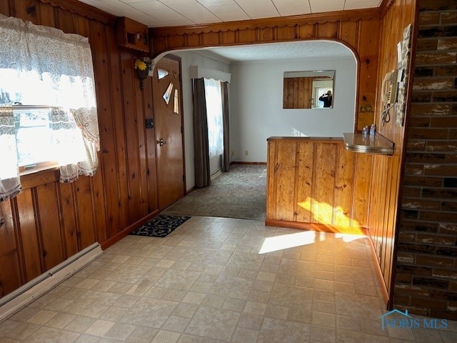 entryway featuring a baseboard heating unit, wooden walls, and light colored carpet